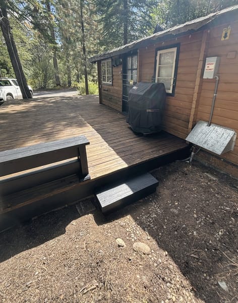 Deck and steps along a cabin with a grill