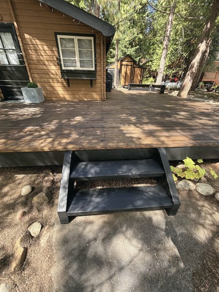 Black-stained steps down from a deck to the path