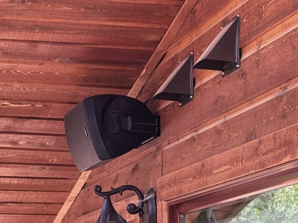 Outdoor speaker and cable hoods under a porch roof